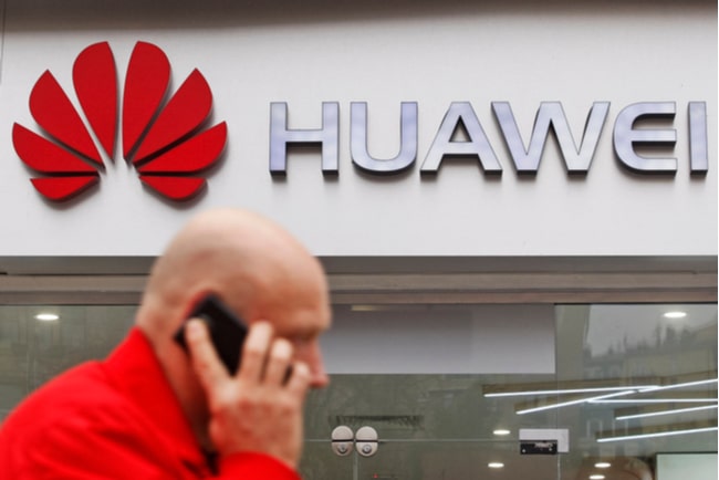 Man pratar i telefon framför Huawei-logga