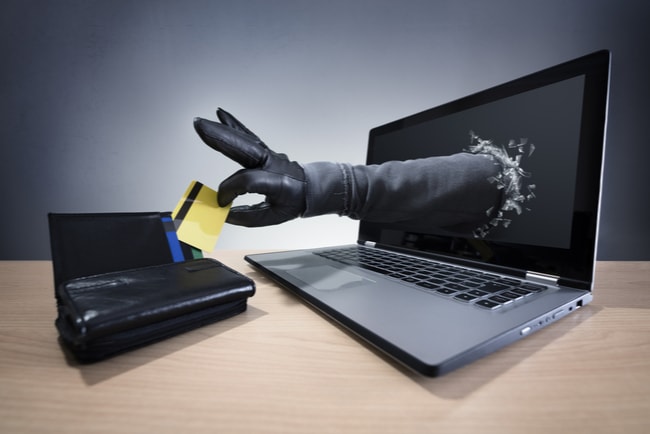 hand sträcks ut ur datorskärm och stjäl kreditkort från plånbok