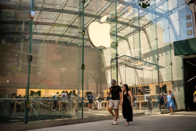 Apples logga på butiksfönster med förbipasserande människor runt om kring.